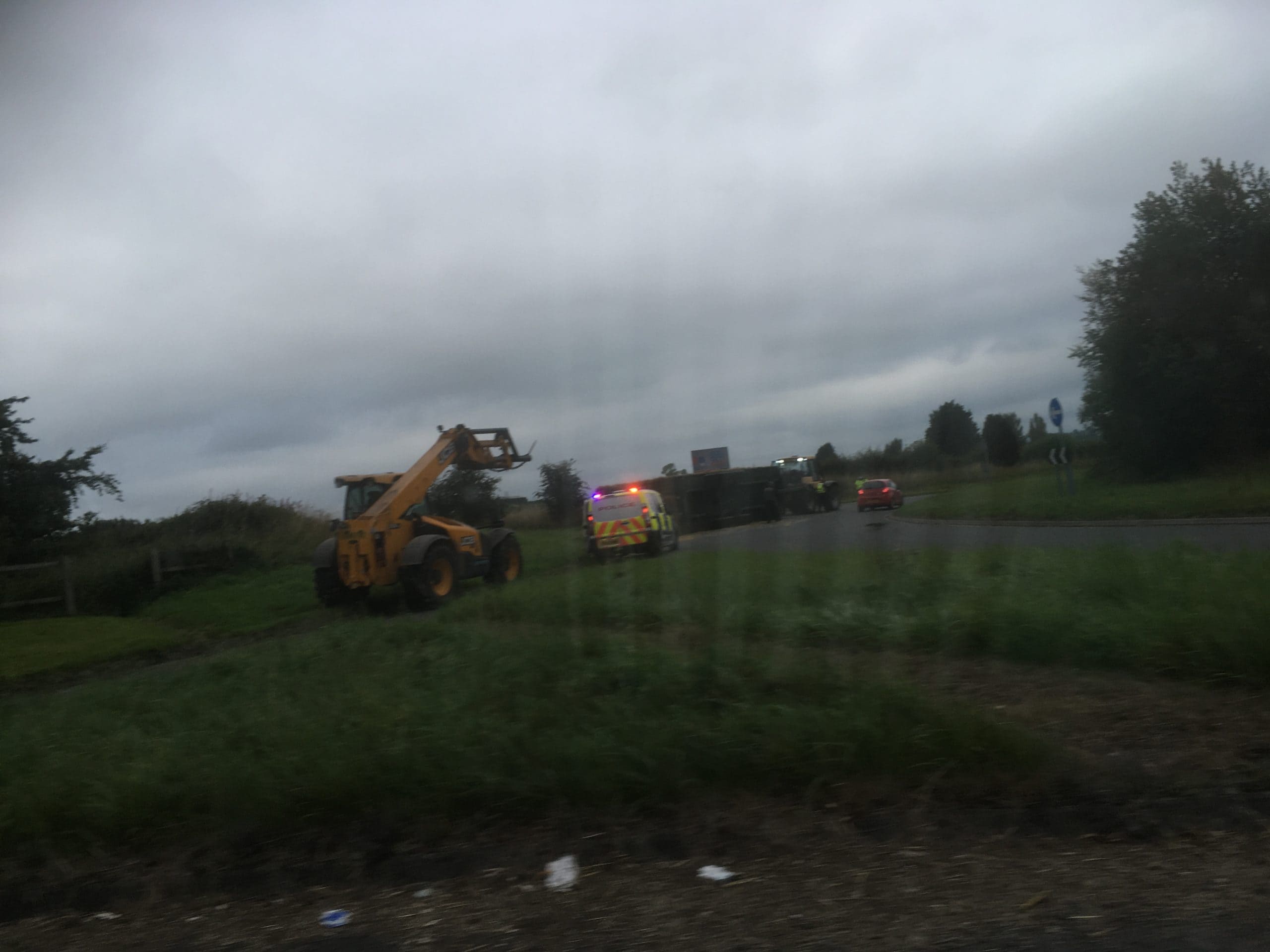 Tractor's trailer overturns and sheds hay load on roundabout into